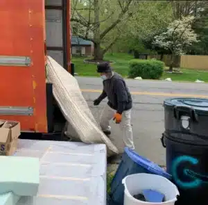 Junk Removal Services in Arlington – MA Junk Removal & Cleaning Services Worker loading mattress and household junk into removal truck in Arlington VA