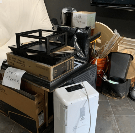 Flat-screen TVs and junk labeled for removal in Falls Church basement