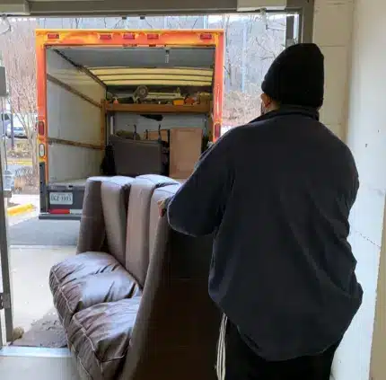 Furniture Removal McLean VA Furniture removal in McLean VA with a worker loading a sofa into a moving truck