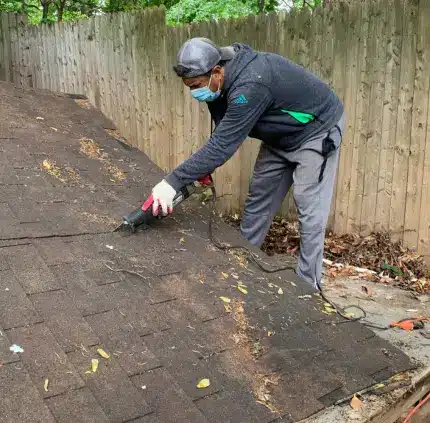 Worker dismantling shed roof during shed removal service in Virginia