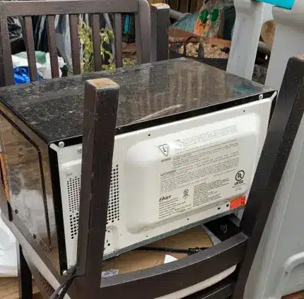 Old microwave placed on chair for appliance removal in Woodbridge VA